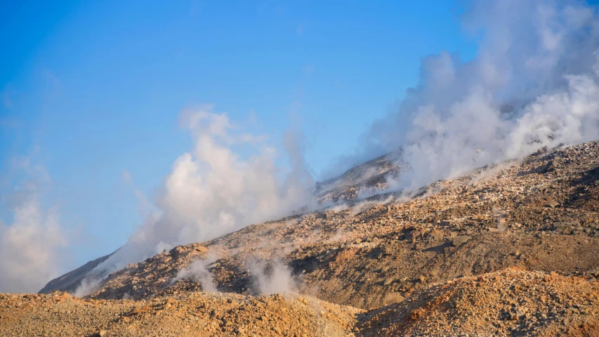 steam billowing out from a mountain on a clear day