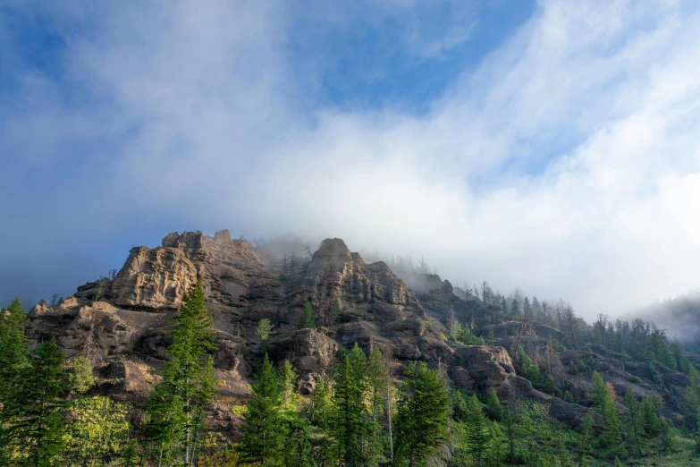 mountains with trees on the top of them on a cloudy day