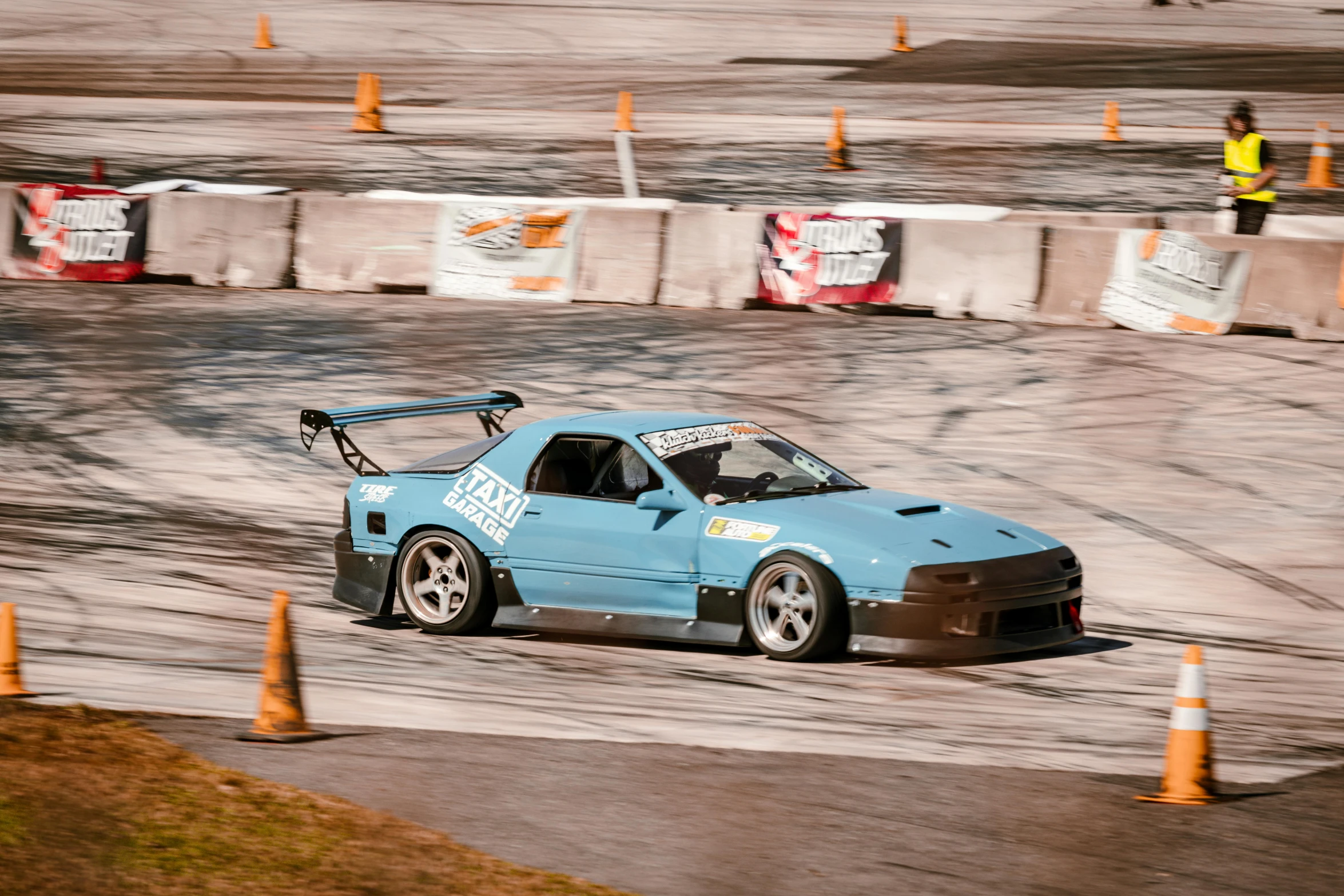 a light blue modified car going around a corner