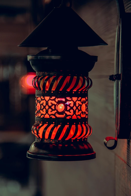 a lit up, red lamp hanging from a wall