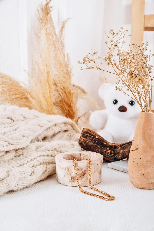 a teddy bear next to a vase with some dry grass in it