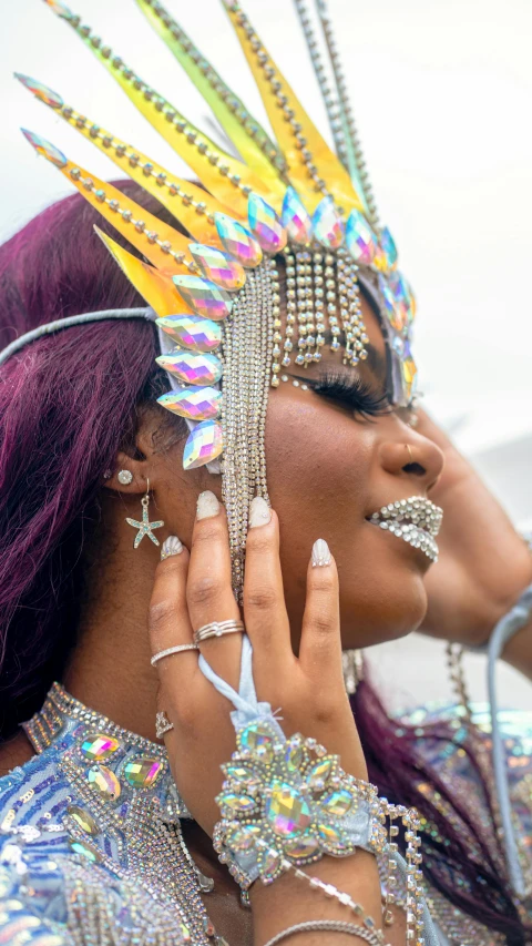 a woman wearing multi colored costumes and holding her hand to the face