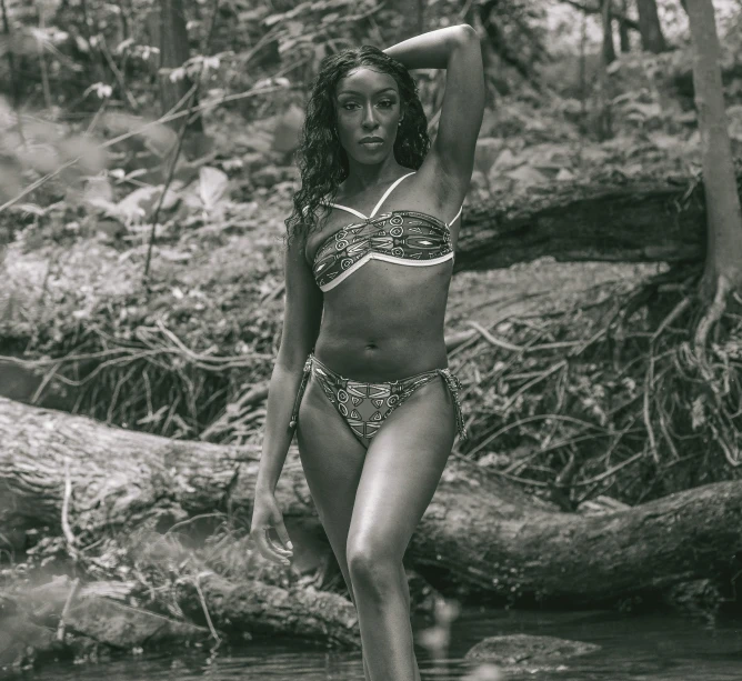 a black and white image of a woman wearing a bikini in the woods