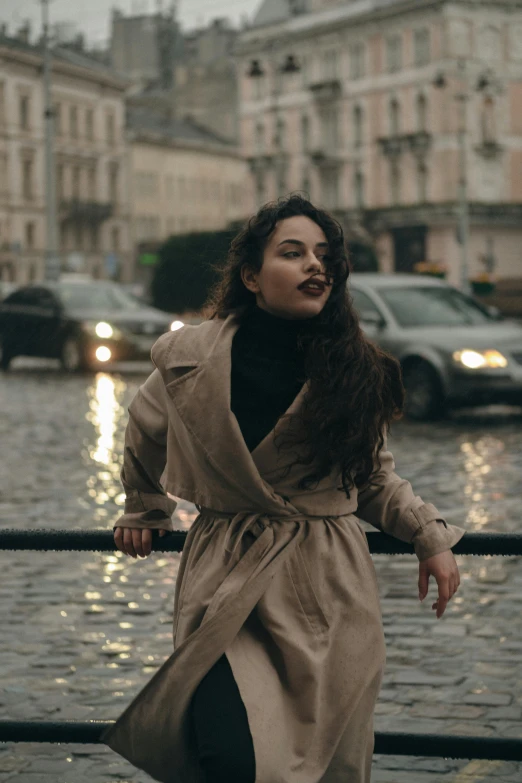 a woman standing on a street corner in the rain