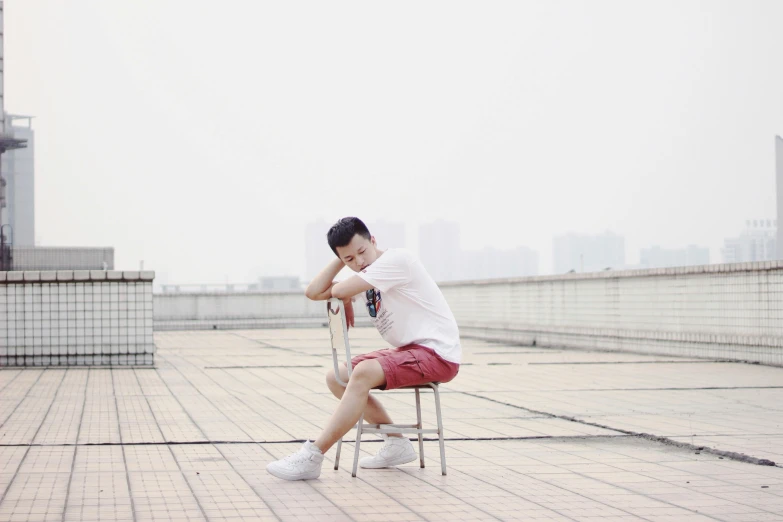 young man sitting on a chair next to a railing