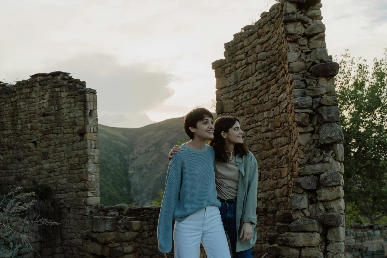 two people standing next to a brick wall