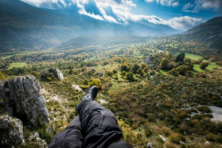 a person with their feet in the air, looking out into the mountains