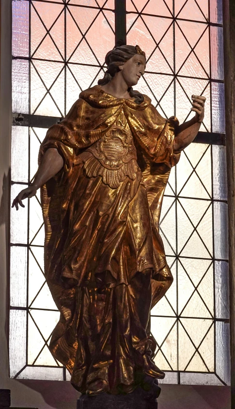 the sculpture in front of the stained glass window is a lady of grace