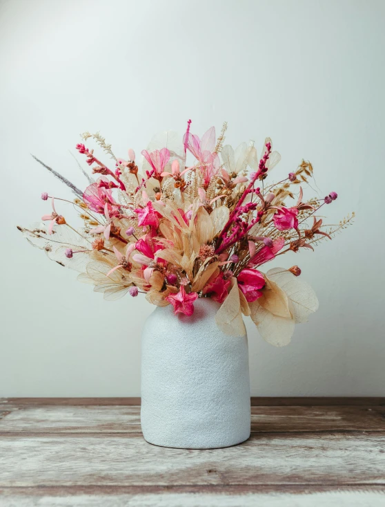 small pink flowers sitting inside of a white vase