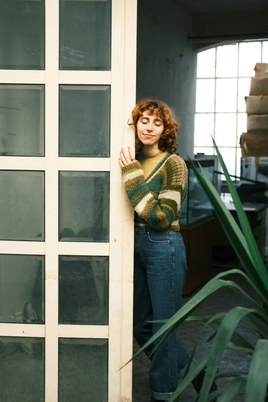 a girl poses in a sweater by a large white door