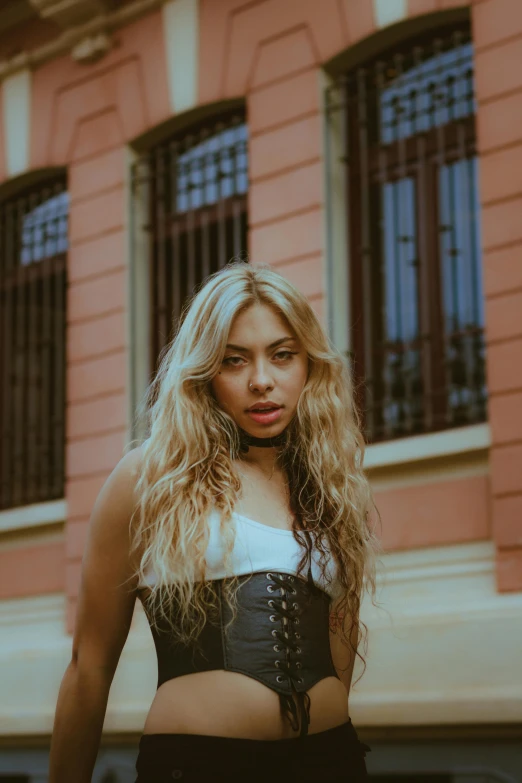 a woman with large  and leather corset standing in front of an old building