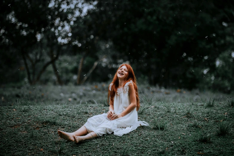 a young woman sitting in the grass laughing