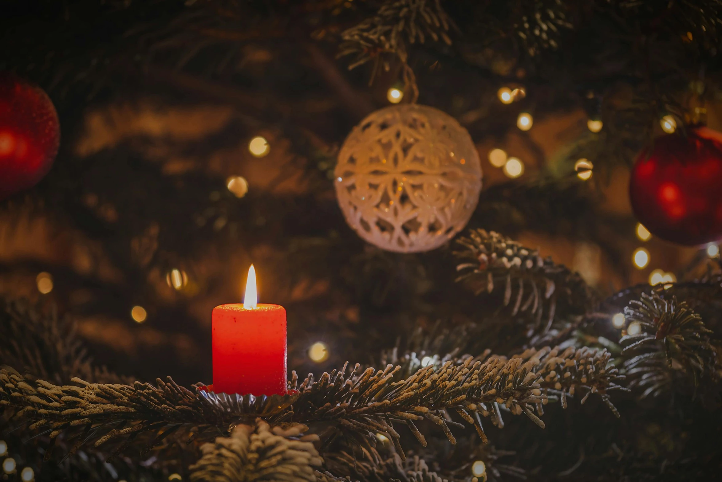 a single red candle with a ball on the top