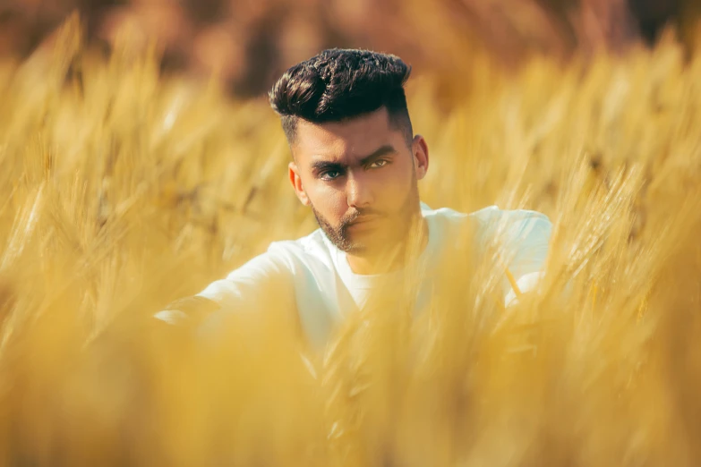 young man in a field of tall grass looking away