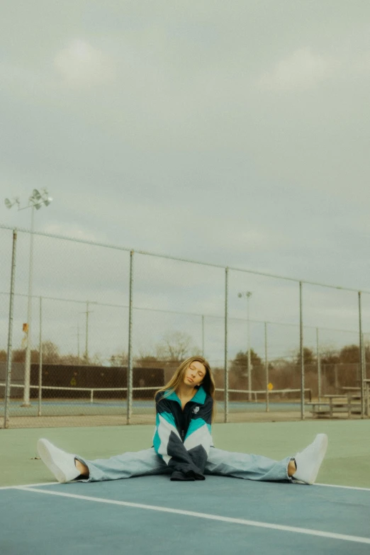 young woman posing on tennis court in blue sweater