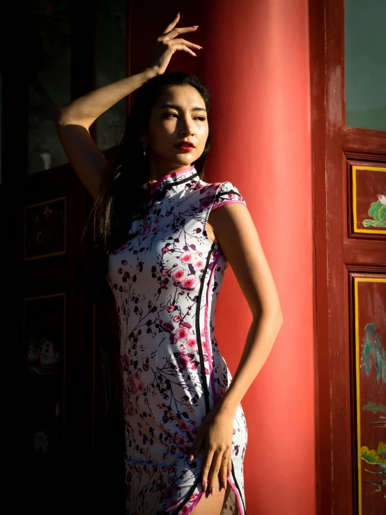 a beautiful woman standing next to a red wall