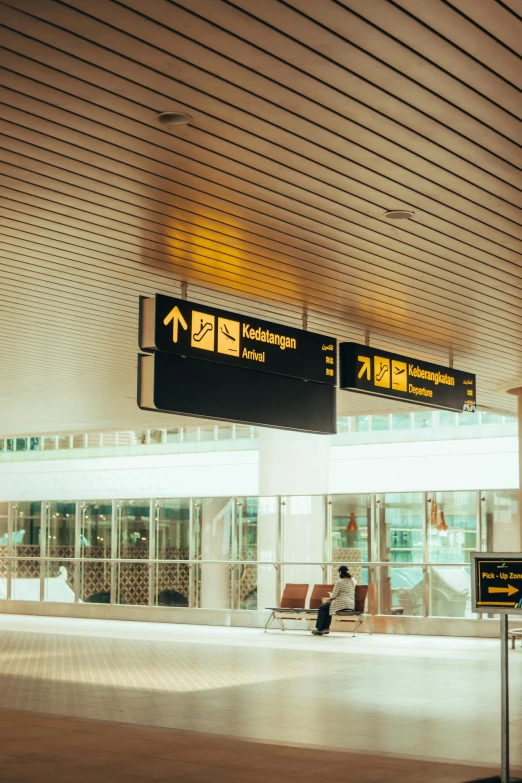 an airport lobby with a directional sign above it