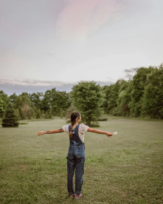 a woman standing in a field with arms spread open