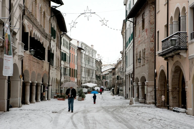 people walking through the snowy streets of old italian buildings