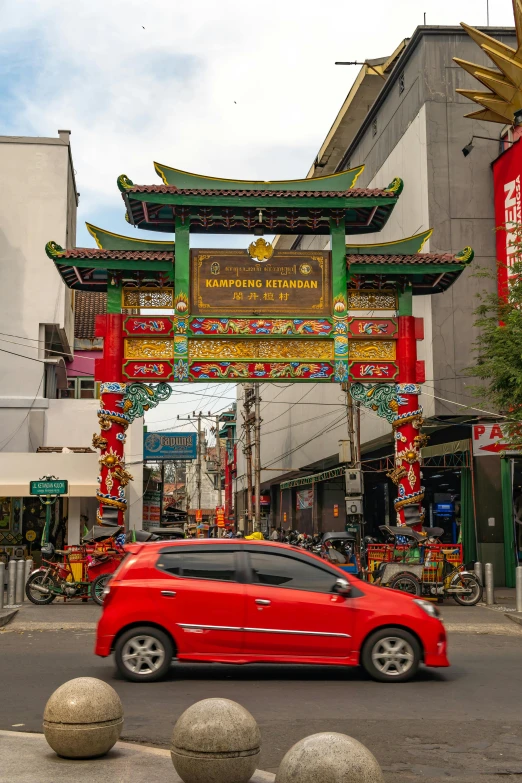 an asian street with a red car driving down it