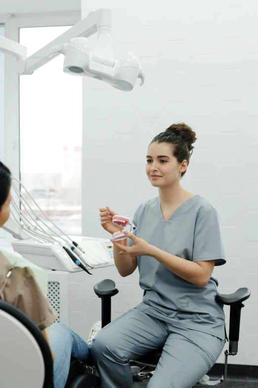 woman at a dental check - up holding a dental floss