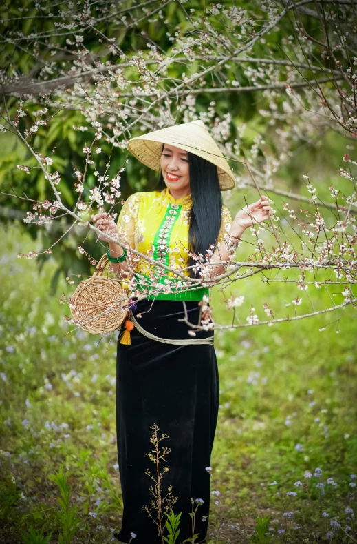 the woman is standing in the field holding a basket of flowers