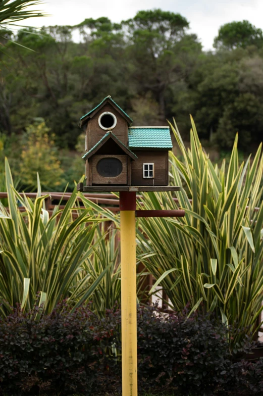 a birdhouse on top of a pole in front of trees