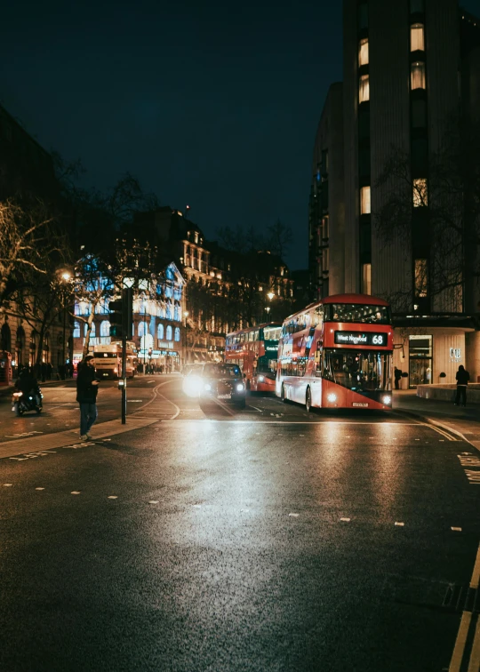 the double decker bus is driving through the city at night