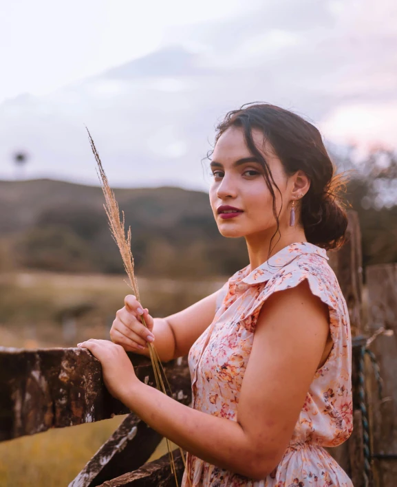 a young woman is standing by a fence