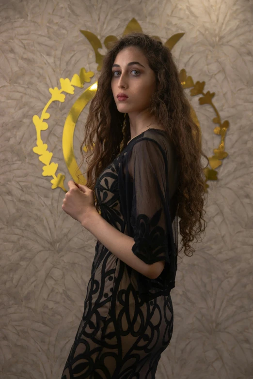 a woman holding a golden plate next to a wall