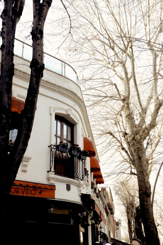 a tall white building with a balcony with a small black balconie on the top