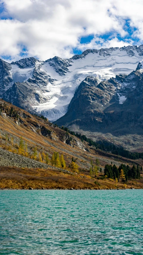 snow capped mountains in the distance next to a body of water