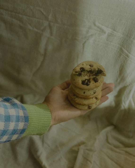 a hand is holding an over sized chocolate chip cookie