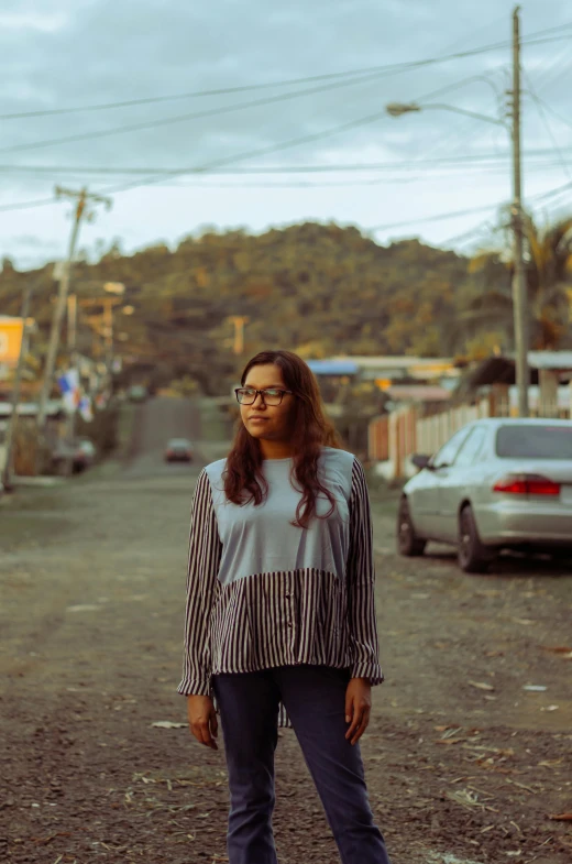 a woman standing on the street with a car parked behind her