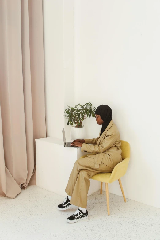 a person sitting on a yellow chair with a laptop in a room