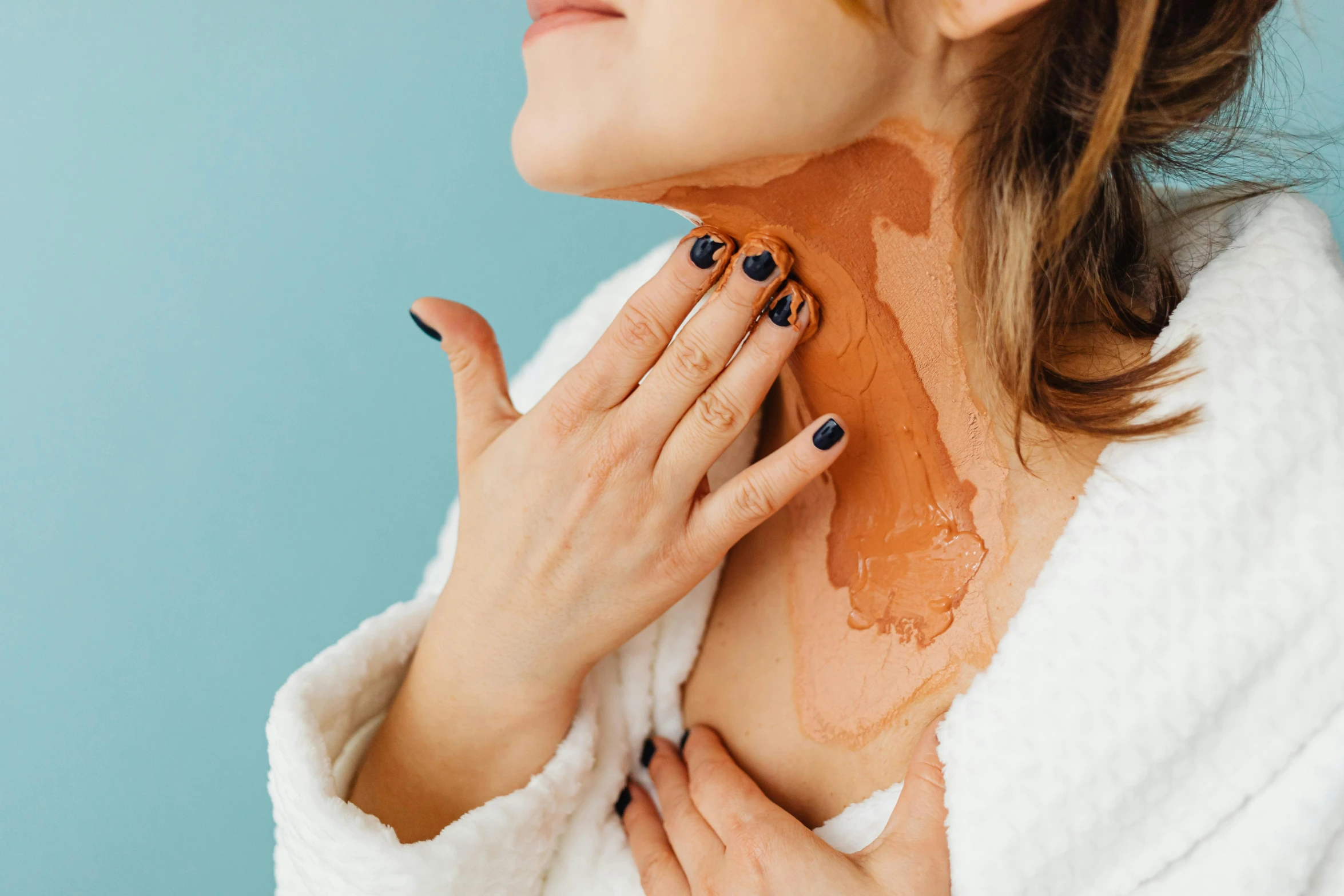 a woman has her hand on her neck and is wearing a sweater