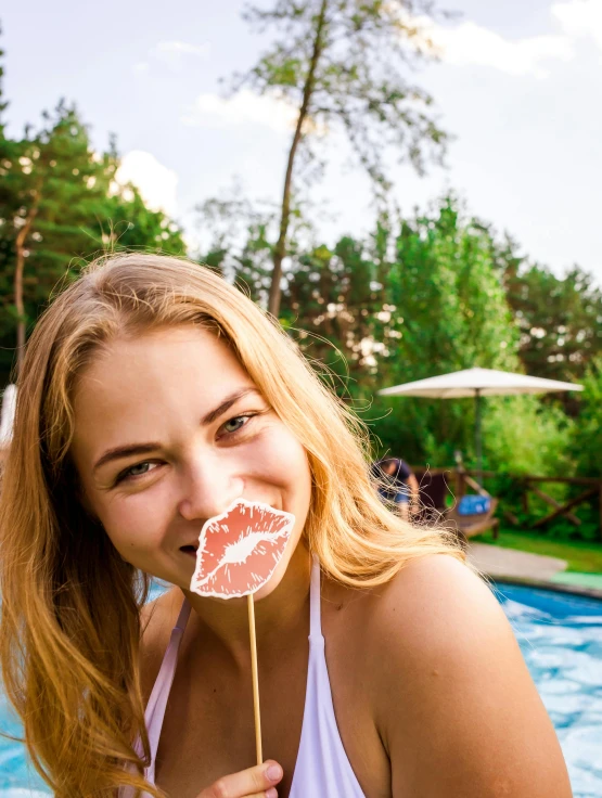 a woman holding a lollipop smiling in a pool