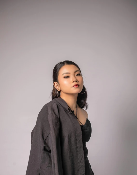 a woman standing on a white background wearing a grey blouse