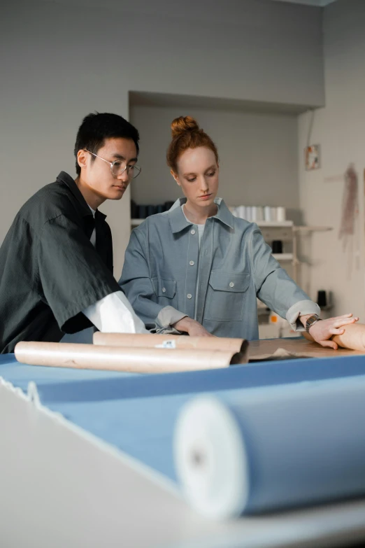 two people work in an office, one of whom is making a paper boat