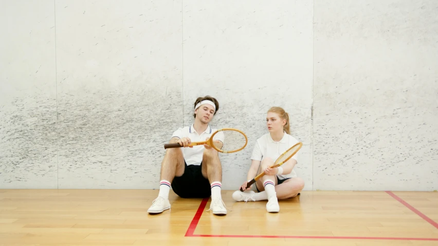 two girls with tennis rackets on the floor