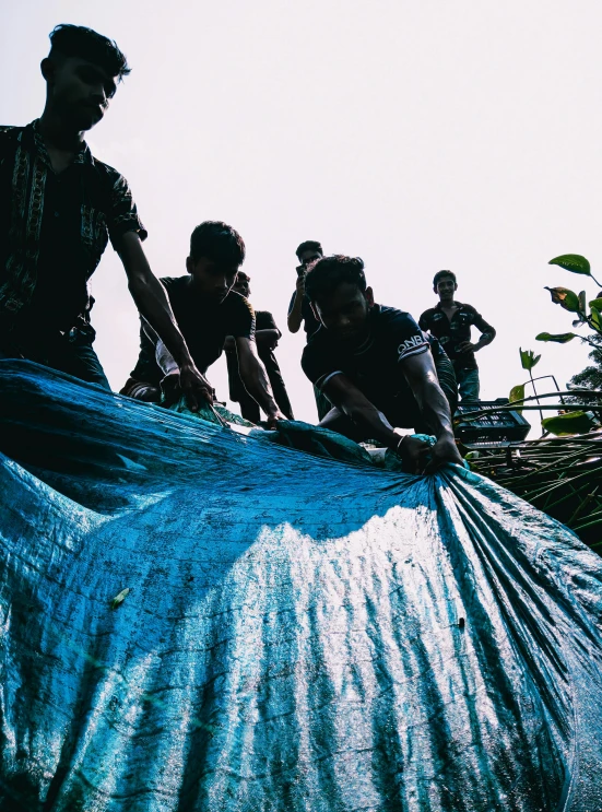 a group of people standing around a large piece of plastic