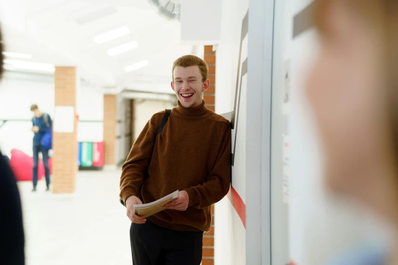 young man wearing a brown sweater smiles at the camera