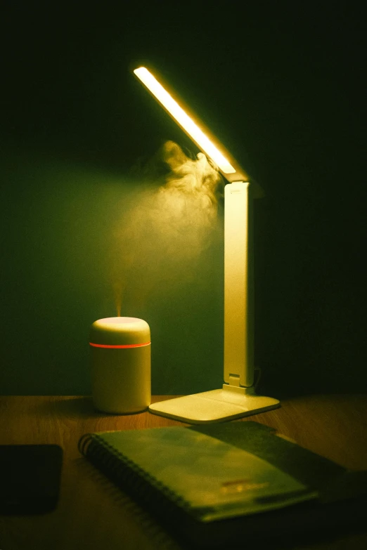 a lit desk lamp sitting next to a notebook
