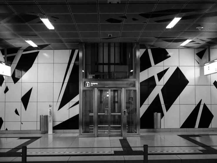 an airport lobby with large doors and black and white wall art