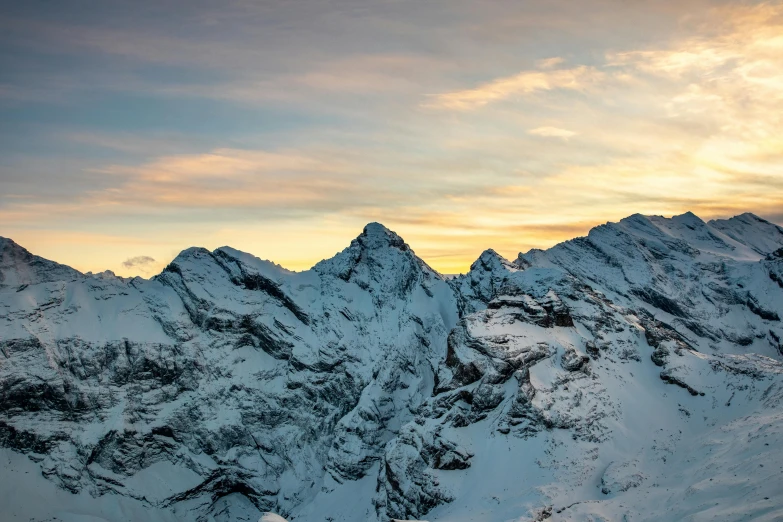 a mountain range covered in snow at sunset