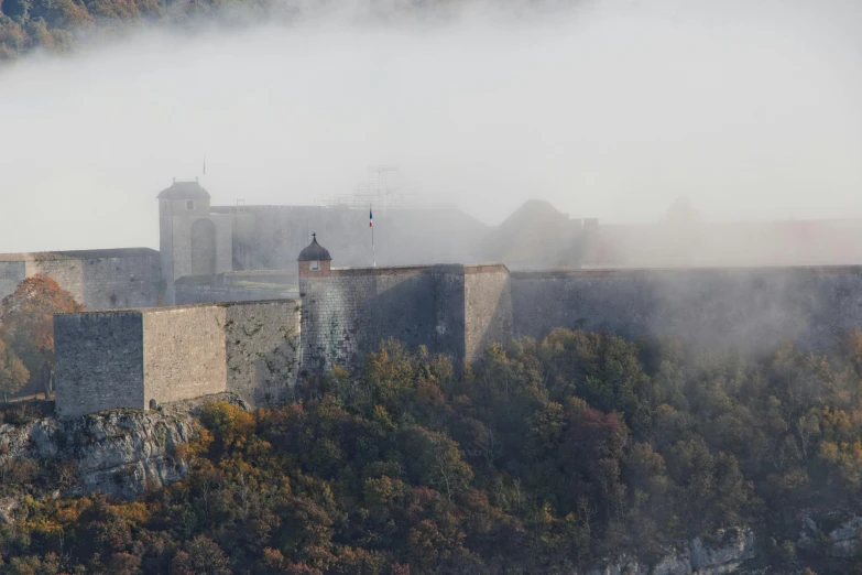 a castle on a cliff with low fog