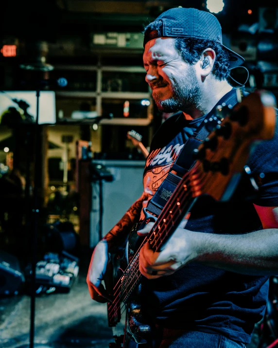 a man standing with his guitar in front of a microphone