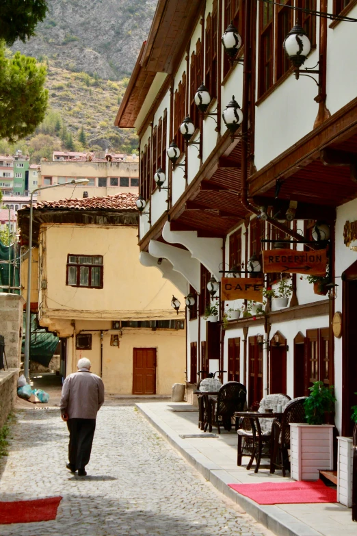 a man walks down the sidewalk in front of the old buildings