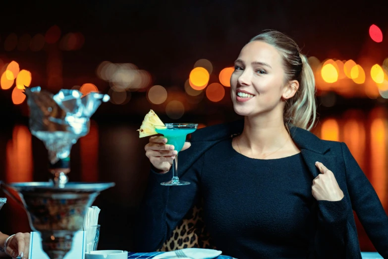 a woman holding up a fruit covered martini in a restaurant