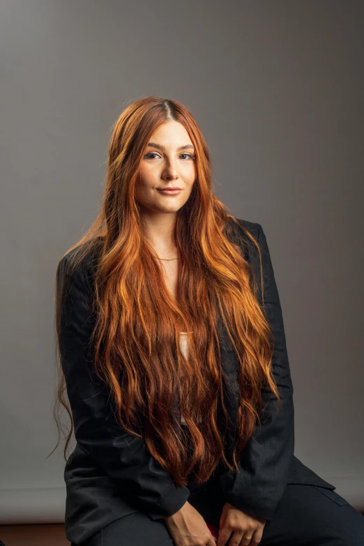 a woman with long red hair is sitting on the ground